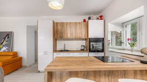 Une cuisine moderne avec des meubles blancs, un îlot central en bois et un four encastré.