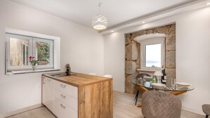 Une cuisine moderne dotée d’un îlot central en bois, de meubles blancs, d’une arche en pierre et d’un coin repas avec une table et des chaises en verre.