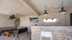 Une cuisine rustique avec un plan de travail en pierre, un banc en bois et des luminaires suspendus.