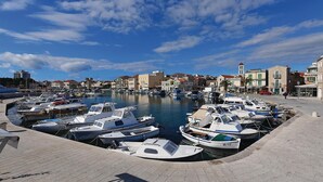 Un port de plaisance où sont amarrés différents types de bateaux, un ciel dégagé et des bâtiments en arrière-plan.
