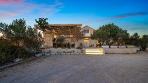 Une maison moderne avec une façade en pierre, une pergola en bois et une allée gravillonnée.