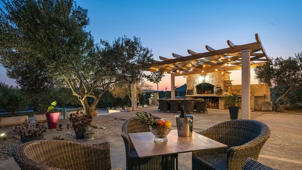 Une terrasse extérieure aménagée avec des meubles en osier, une cheminée en pierre et une pergola.