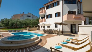 A pool area with lounge chairs, a hot tub, and outdoor seating.