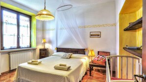 Une chambre d’hôtel avec un lit, des lampes de chevet, une fenêtre avec des rideaux, une table de chevet et une chaise.