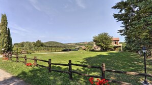 Un paysage rural avec une clôture en bois, un bâtiment doté d’un toit rouge et un ciel dégagé.