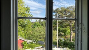 A view through a window of a rural area with a red barn, white fence, and greenery. - 4 bedroom pet friendly home in Farsund (Farsund)