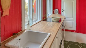 A kitchen with a wooden countertop, a white sink, and a white door. - 4 bedroom pet friendly home in Farsund (Farsund)