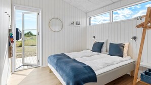Ett sovrum med en säng, en rund spegel och ett fönster.