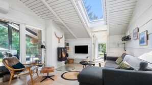 A modern living room with a fireplace, a sofa, a chair, and a TV mounted on the wall.