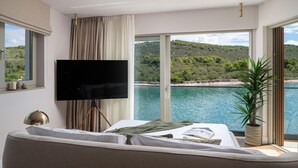 A bedroom with a bed, a TV, a large window with a view of a body of water and hills. - Stunning home in Kali (Kali)