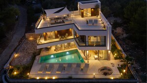 A modern multi-story house with a swimming pool, outdoor seating, and a well-lit patio area. - Stunning home in Kali (Kali)