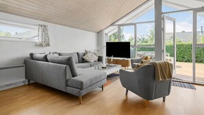 En moderne stue med en grå sofa, et sofabord og et fjernsyn.