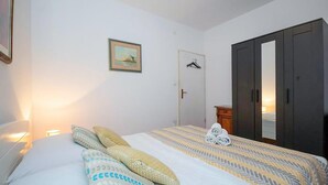 A bedroom with a bed, pillows, a wardrobe, a door, and a framed picture on the wall. - Nice apartment in Omis with WiFi (Omis)