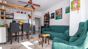 A modern living room with a teal sofa, a dining area with chairs and a table, and a kitchen with a ceiling fan. - Nice apartment in Omis with WiFi (Omis)