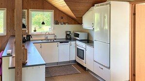 Une cuisine compacte équipée d’un four, d’un micro-ondes et d’un réfrigérateur intégrés.