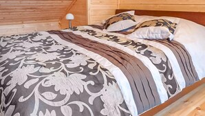 Une chambre dans une cabane en bois, avec un lit, des oreillers et une table de chevet sur laquelle se trouve une lampe.