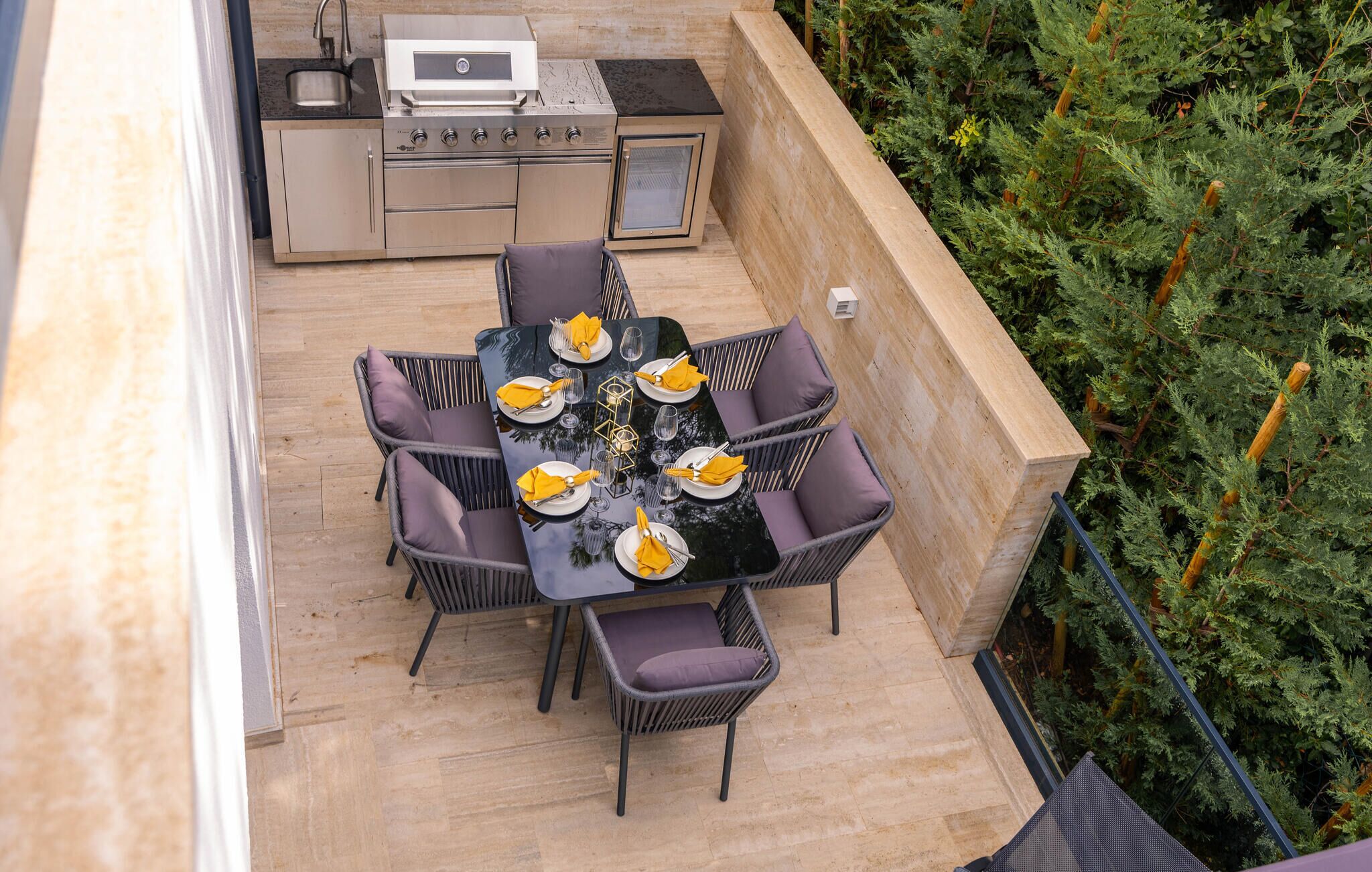An outdoor patio with a dining table set for four, surrounded by wicker chairs with cushions.