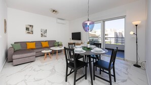 A modern living room with a grey sofa, a dining table set for four, and a balcony with a view. - 2 bedroom awesome apartment in Seget Donji (Seget Donji)