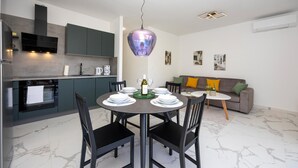 A modern kitchen with dark cabinets, a built-in oven, and a dining area with a round table set for four. - 2 bedroom awesome apartment in Seget Donji (Seget Donji)