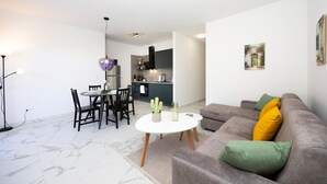 A modern living room with a grey sofa, a round coffee table, and a dining area with a table and chairs. - 2 bedroom awesome apartment in Seget Donji (Seget Donji)