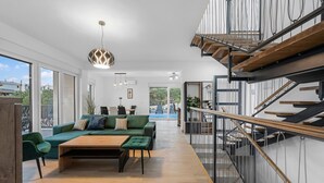 Una sala de estar moderna con un sofá verde, una mesa de centro de madera y una escalera con barandilla de vidrio.