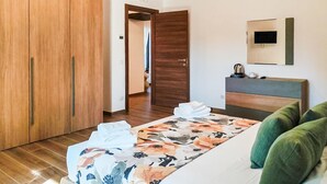 Ein Hotelzimmer mit Bett, Schrank, Nachttisch mit Wasserkocher und Spiegel an der Wand.