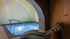 Ein Wellnessbereich mit Whirlpool, Liegestuhl und Holzschrank.