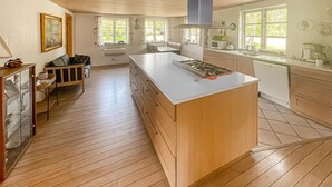 Una cocina amplia con suelo de madera, una isla central y una zona de comedor con mesa y sillas.