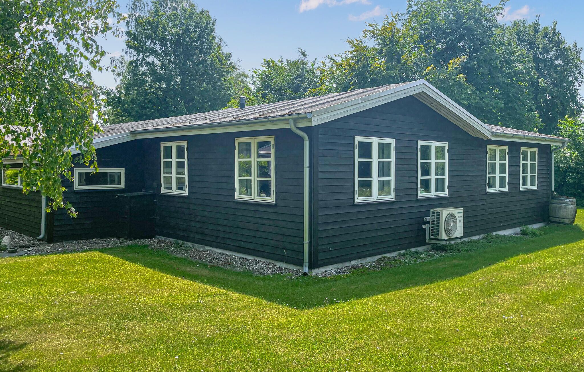 Une maison à deux étages, à l’extérieur sombre, avec des moulures blanches autour des fenêtres et des portes, et un petit garage attenant.