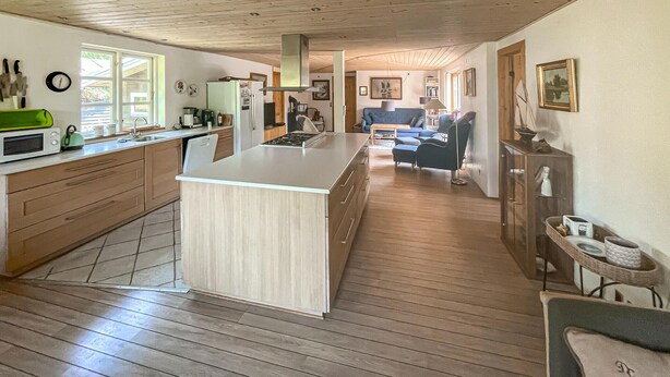 Una cocina amplia con pisos de madera, una isla central y un comedor con un sofá azul.