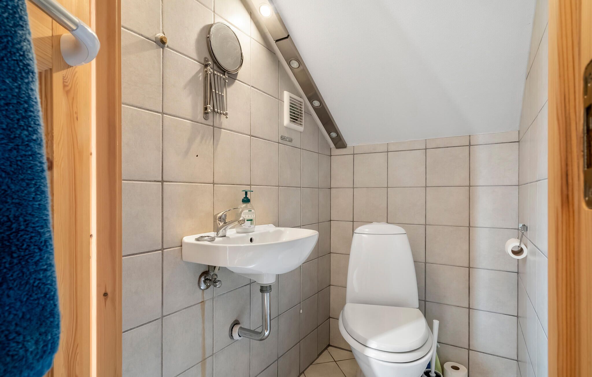 A small, compact bathroom with a white sink, toilet, and a mirror.
