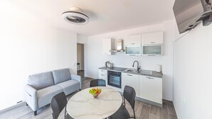 A compact living space with a kitchenette, a sofa, a dining table with fruit, and a TV mounted on the wall. - 2 bedroom lovely apartment in Stanici (Stanici)