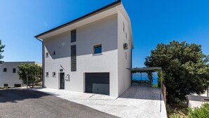 A modern two-story building with a garage, a covered outdoor area, and a view of the sea. - 2 bedroom lovely apartment in Stanici (Stanici)