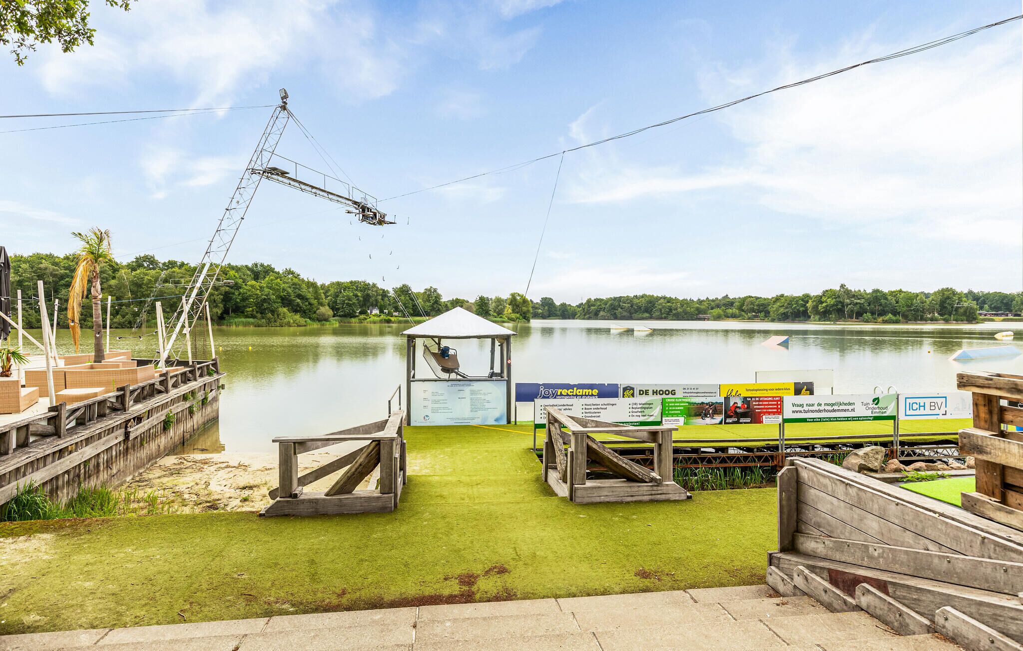 A lakeside dock with a small pavilion, a fishing boat, and a grassy area.