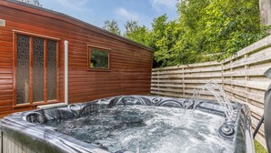 Un bain à remous dans un jardin, avec des murs et une clôture en bois.