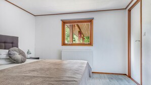 Une chambre à coucher avec un lit, une table de chevet, une fenêtre et un radiateur.