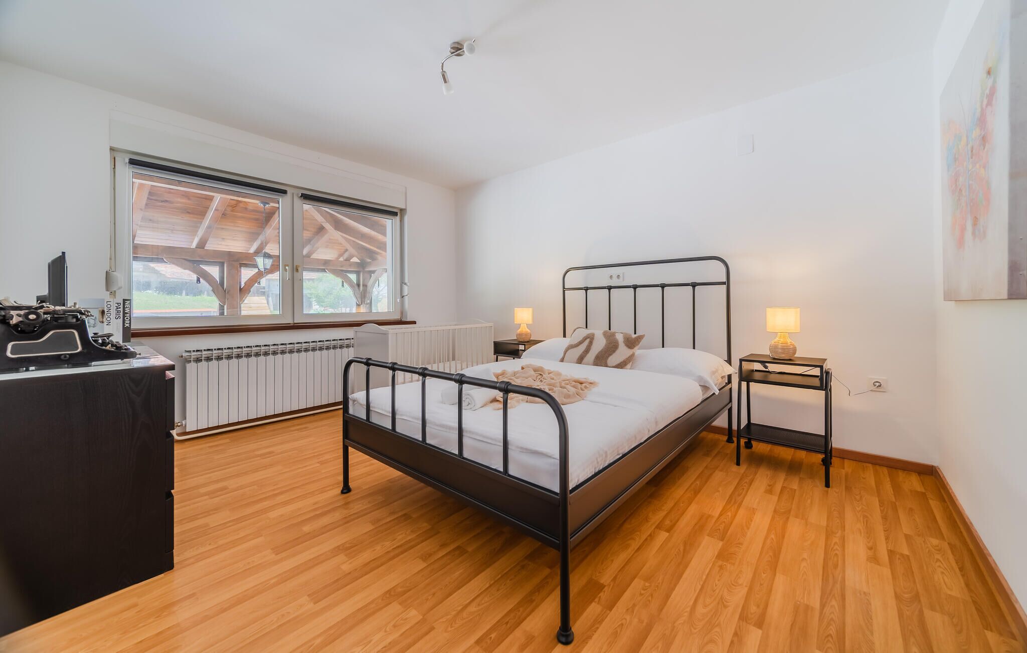 Et soveværelse med seng, sengeborde, en radiator, et vindue og et skrivebord.