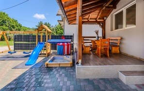 A wooden play structure with a slide, a small table with chairs, and a covered seating area. - Stunning home in Paljugi with sauna (Paljugi)