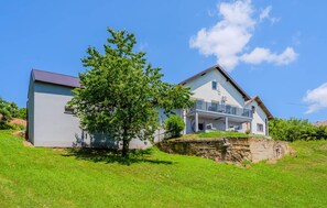 A two-story house with a balcony and a stone wall. - Stunning home in Paljugi with sauna (Paljugi)