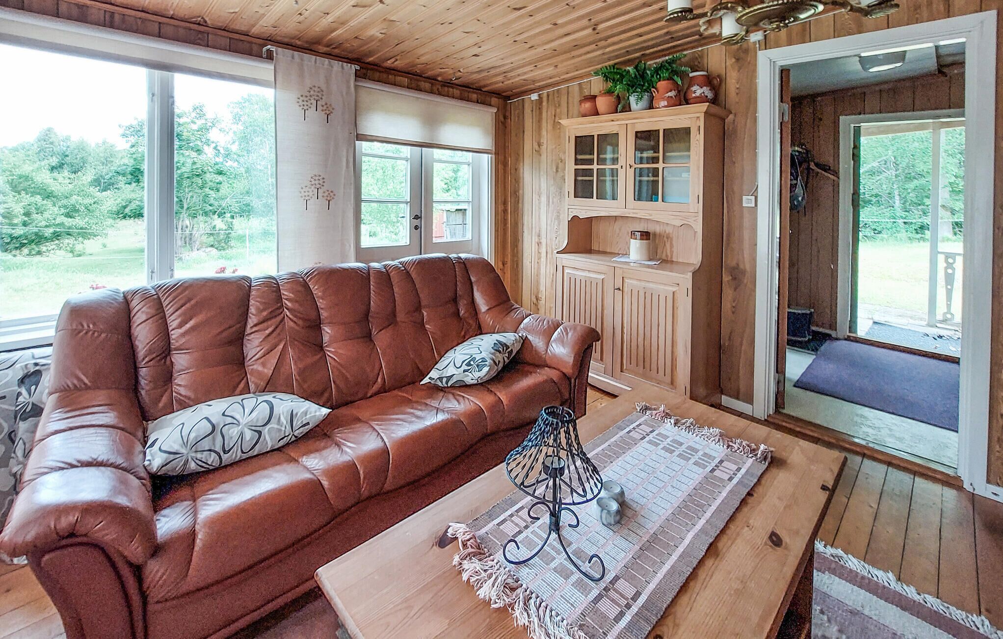 Een gezellige kamer met een leren bank, een houten kast en een raam met uitzicht op groen.