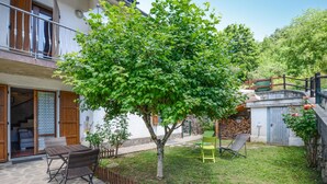 A courtyard with a tree, outdoor furniture, and a stone floor.