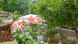 A garden with blooming flowers, a stone wall, and a wooden deck.