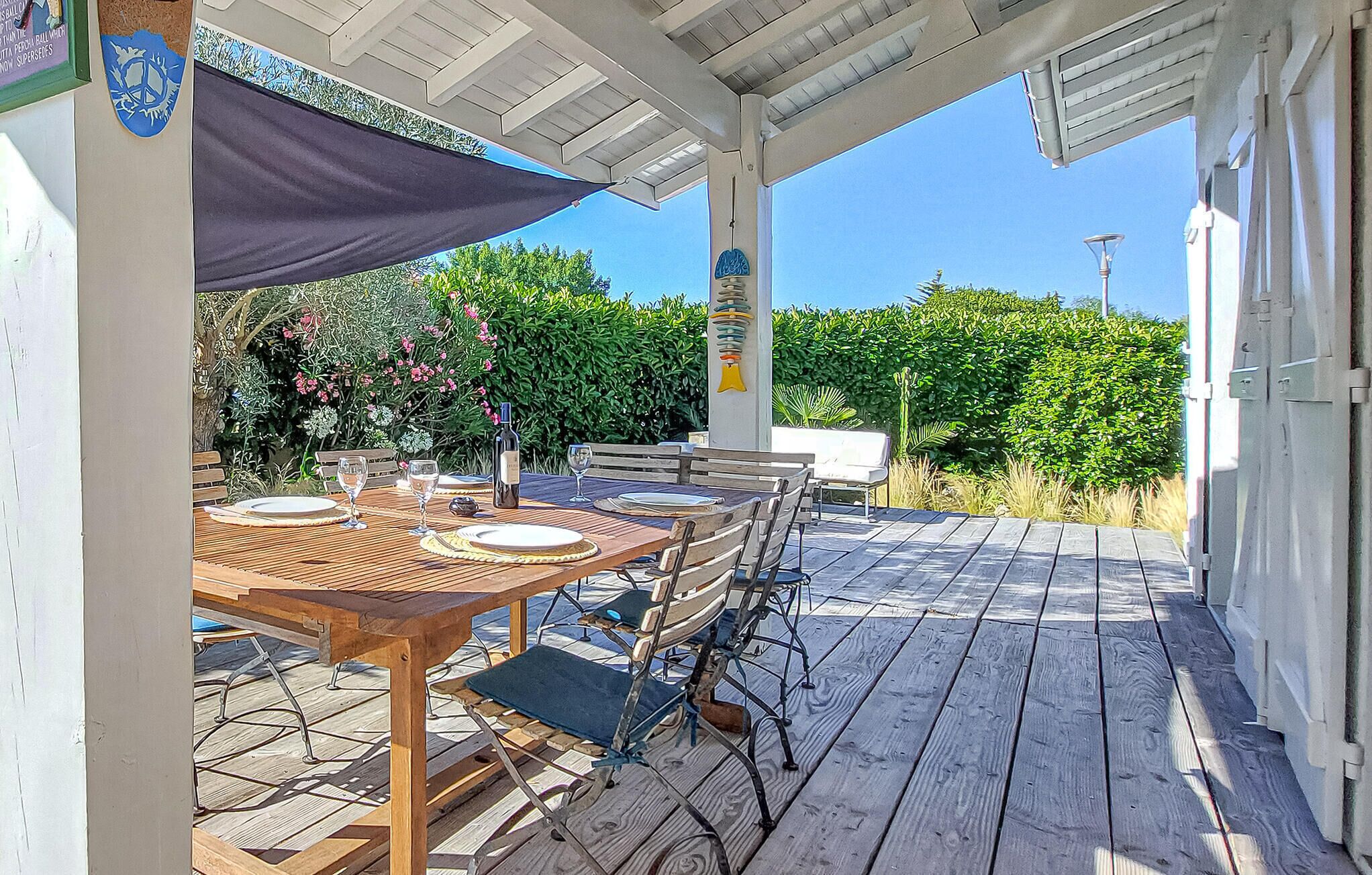 Une terrasse extérieure avec une table en bois dressée pour le repas, entourée de chaises en métal.