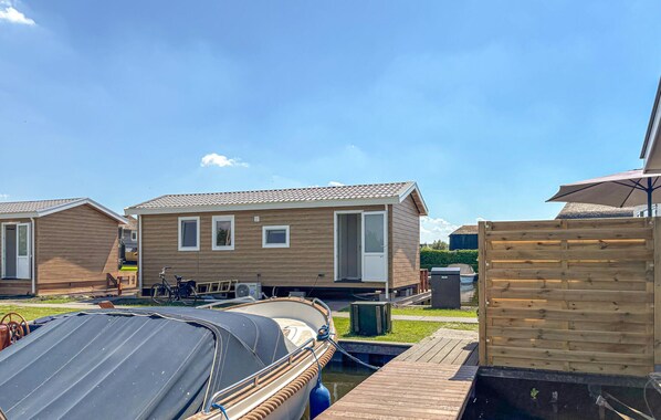 Une rangée de maisons mobiles en bois, avec un bateau amarré devant.