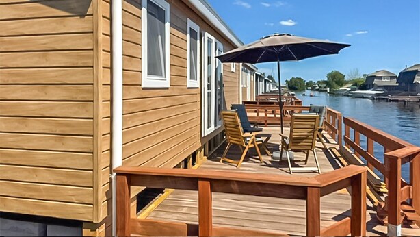 Een houten terras met tuinmeubilair en uitzicht op een waterlichaam.