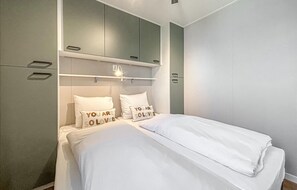 Une chambre à coucher avec un lit, deux oreillers décorés d’inscriptions, une table de chevet et une armoire.