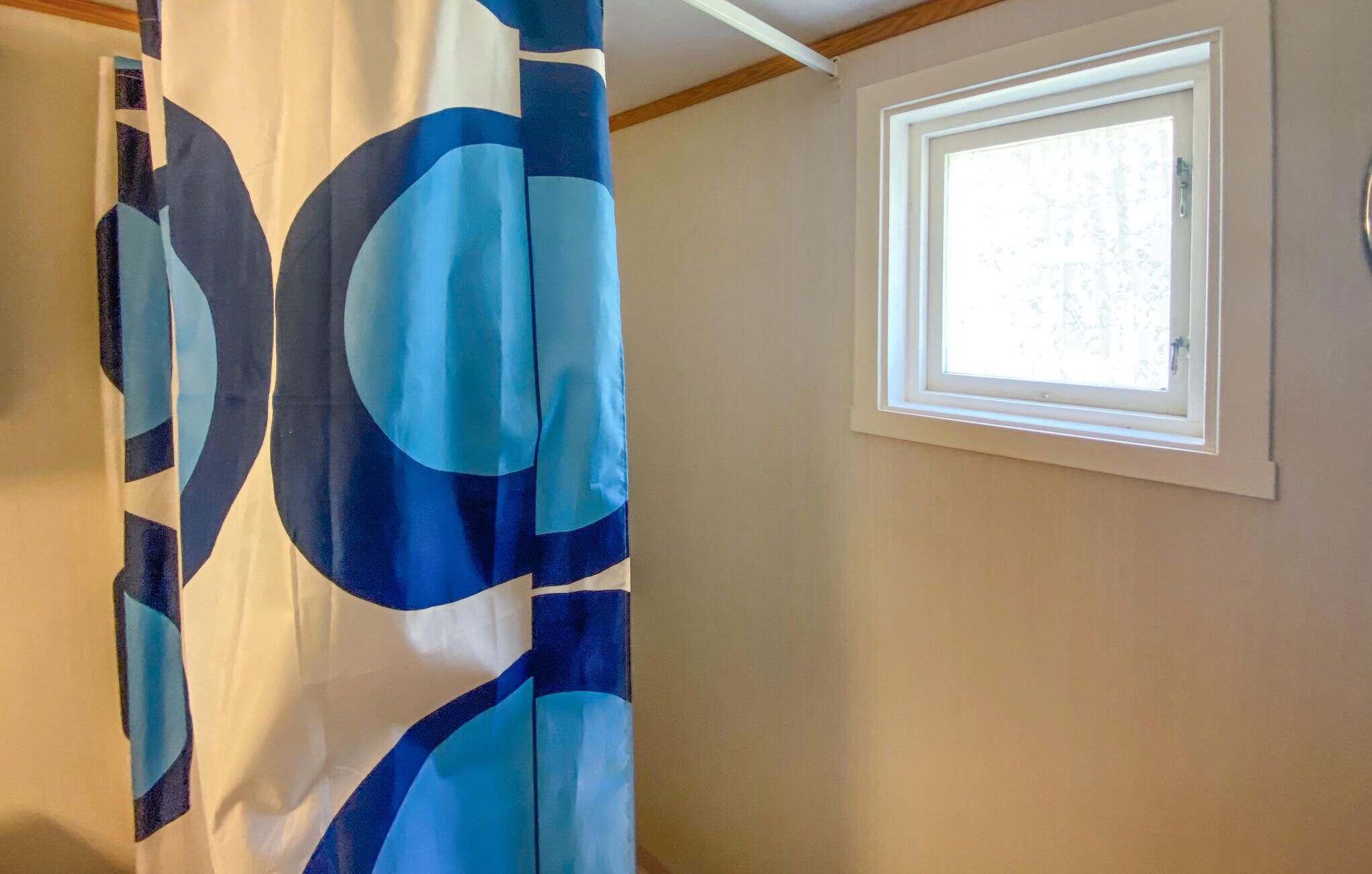 Ein Zimmer mit Fenster und Vorhang mit blau-weißem Muster.