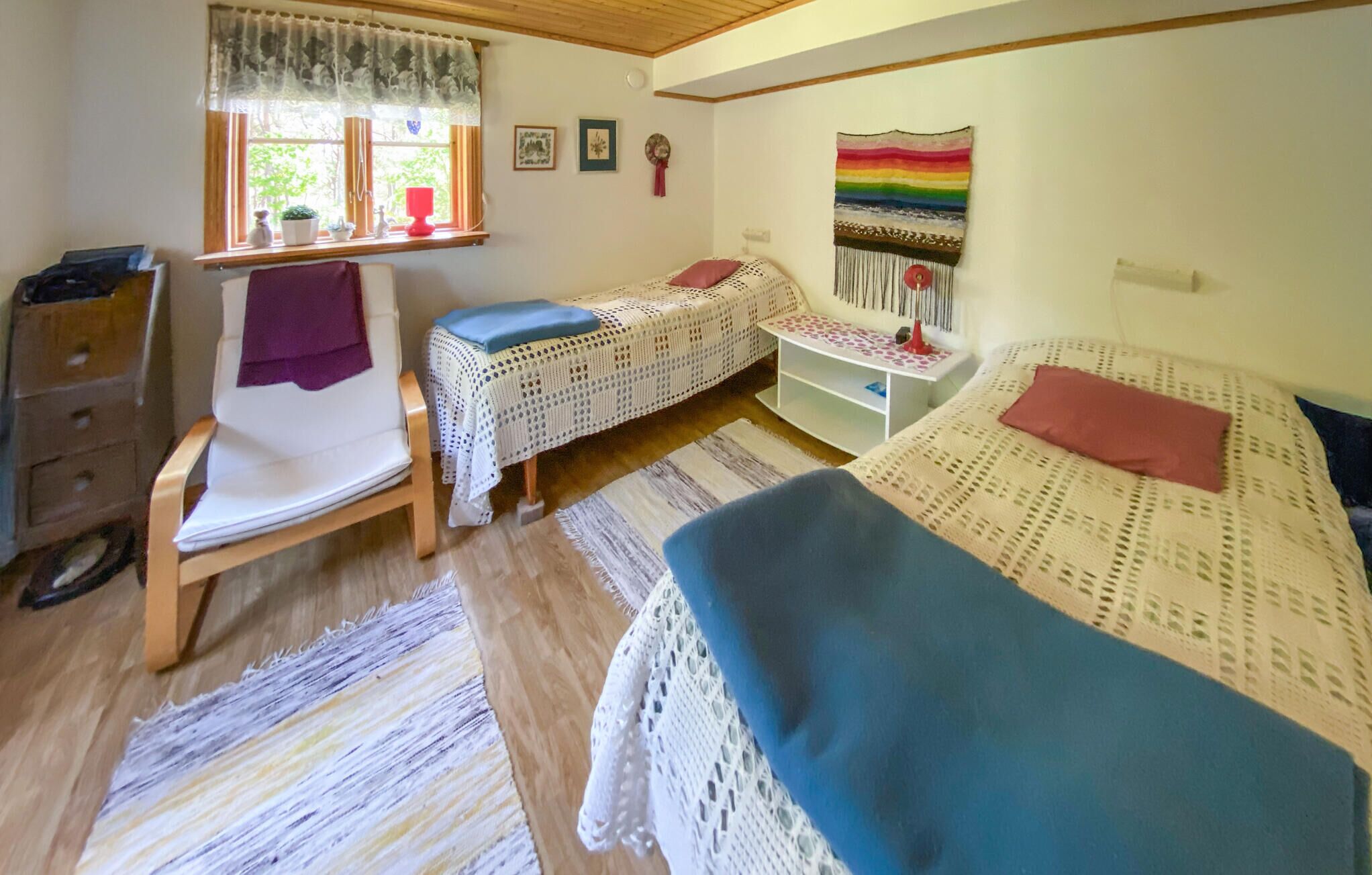 Una habitación acogedora con dos camas, una silla, una mesita y una ventana con cortinas.