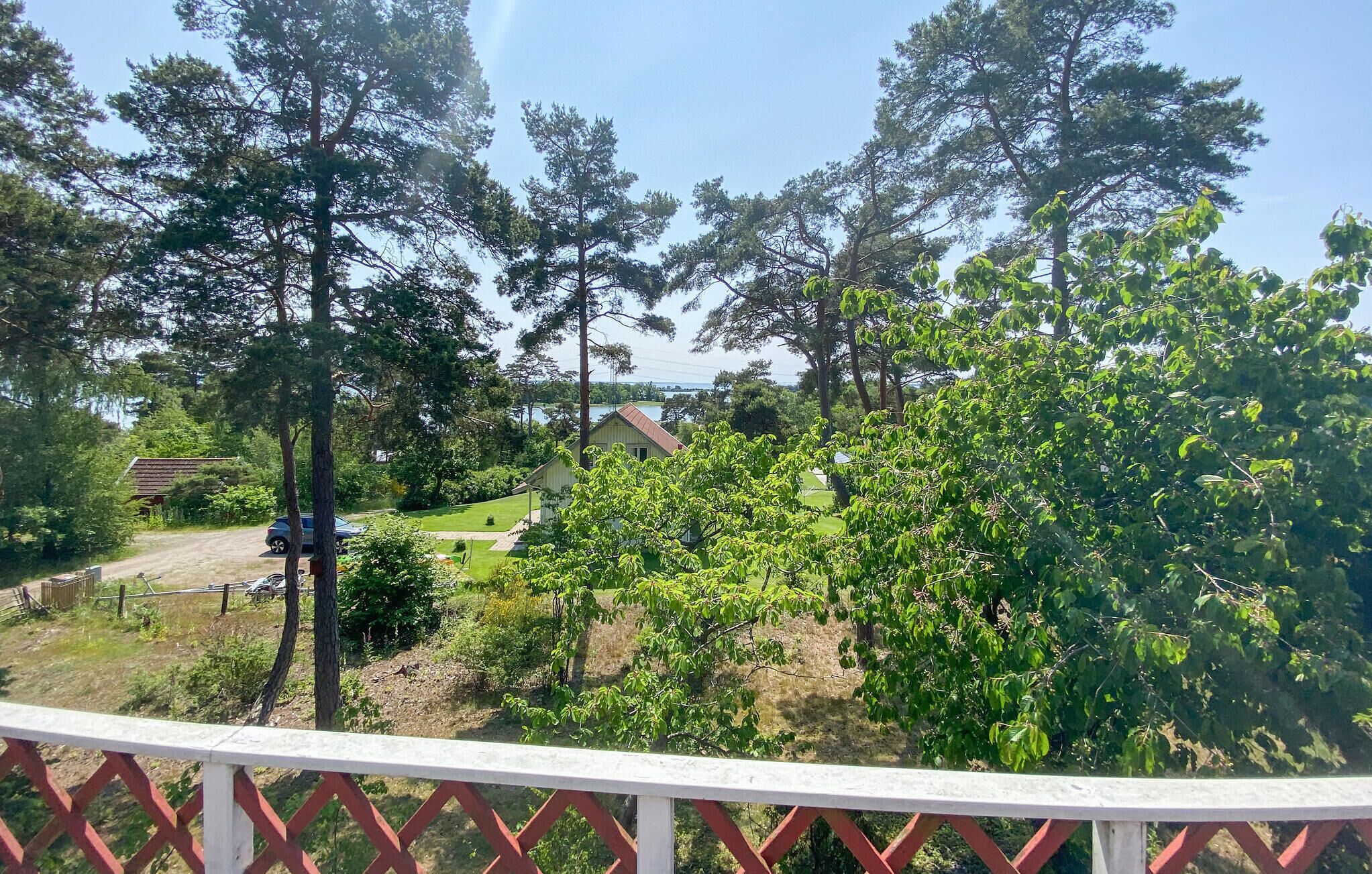 Een woongebied met een huis, een omheind erf en vrij uitzicht op de omliggende bomen en lucht.