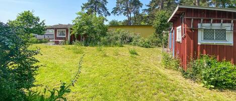 Ett bostadsområde med två hus, ett rött och ett gult, omgivet av grönska och träd.